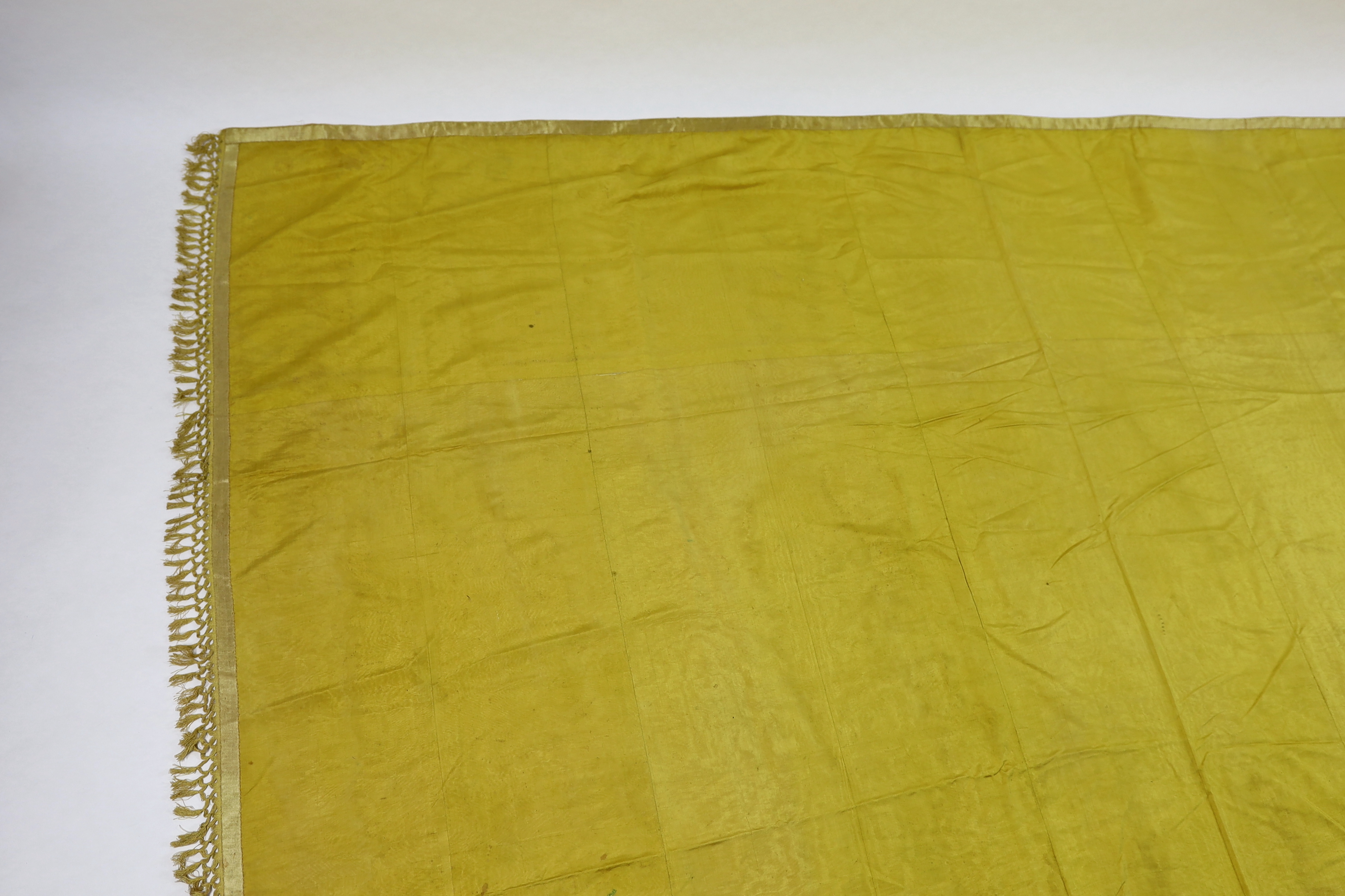 A large Regency yellow silk curtain, with fringed base, French short loom ribbed silk panels made into a wide curtain, with fringing on each side and at the bottom, 9ft wide x 8ft 6in. long